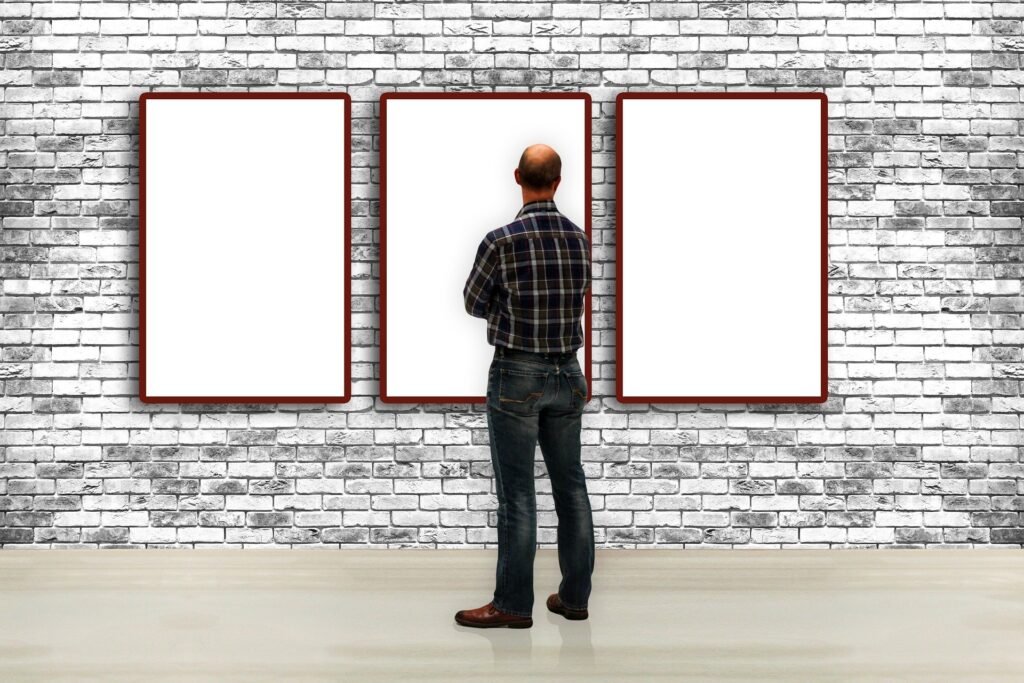 Bedroom with one large central artwork above bed, surrounded by smaller framed pieces, neutral modern decor, and soft bedding