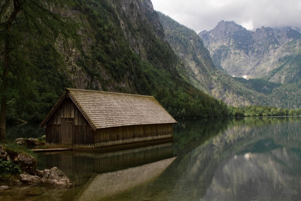 Bright lake house bedroom with large window facing calm lake, white bedding, light wood furniture and soft natural sunlight