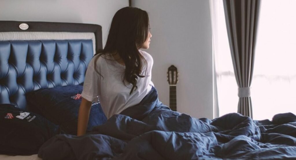 Coastal bedroom lighting layers with warm bulbs: ambient ceiling light, bedside task lamps, and soft accent lighting