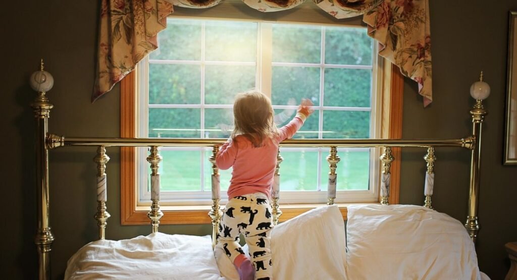 Lake house bedroom with bed facing large window, beautiful lake view, light curtains and simple modern decor
