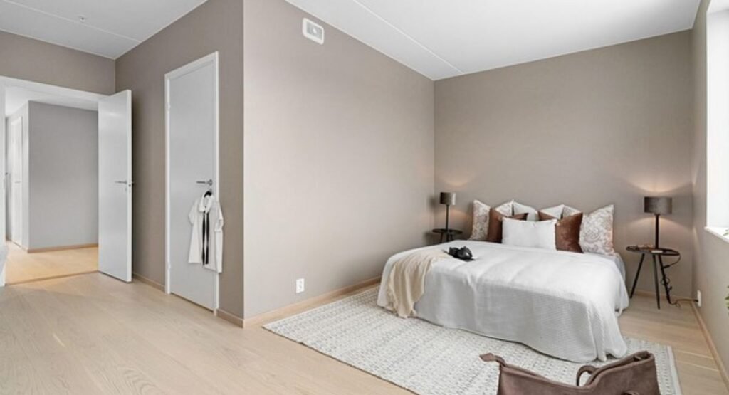 Warm neutral paint samples on bedroom wall viewed in daylight and at night to compare undertones